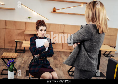 Junge auszubildende Gefühl sorgen, hören auf ihre strenge Chefin Stockfoto