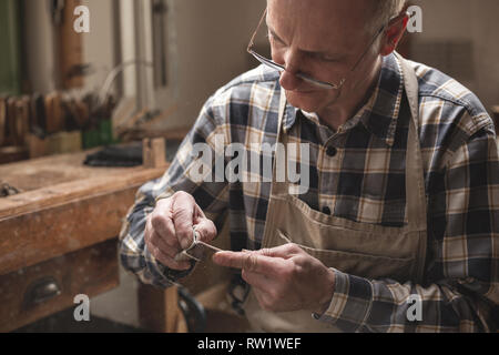 Reifen artisan In einem Workshop nach unten Schleifen einer Geige Bogen manuell Stockfoto