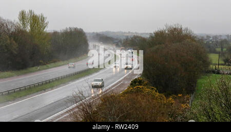 Moira, Nordirland. 04. März 2019. UK Wetter - nasse und kalte Frühling Tag mit starken Regen, Schneeregen und Schnee und Wasser Duschen, die alle in der Mischung. Verkehr auf der Autobahn mit Licht am nassen Wetter auf der M1. Quelle: David Hunter/Alamy Leben Nachrichten. Stockfoto