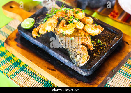 Forellen auf dem Stein; ganze Forelle, auf heißen Stein serviert mit Garnelen Stockfoto