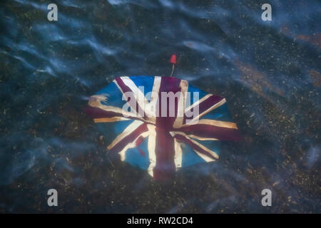 Kaputte Regenschirm mit Union Jack auf Ihn, in seichten Fluss verworfen. Stockfoto