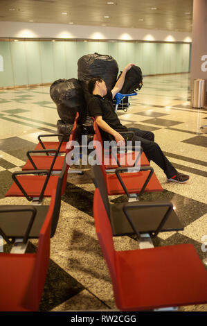 01.03.2019, Singapur, Republik Singapur, Asien - ein Fahrgast Schlafen neben seinem Gepäck in einem öffentlichen Bereich auf der Flughafen Singapur Changi. Stockfoto