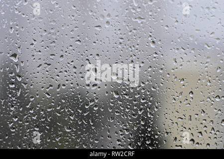 Regen fällt auf Fensterglas Hintergrund bei regnerischen Tag verschwommen außerhalb himmel wolke blau Textur - Bild Stockfoto