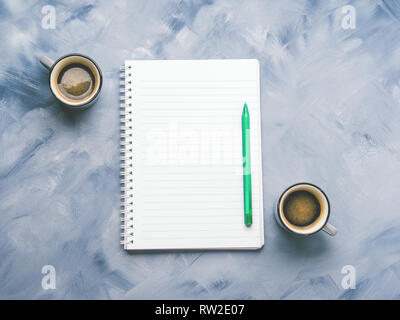 Zwei Kaffeetassen und Leere notepad Seite mit Stift auf Sky Blue gemalten Hintergrund. Minimale flach Stockfoto