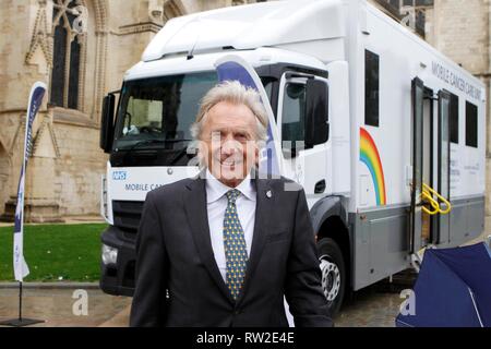 Derek Bell MBE, der äußerst erfolgreichen Rennfahrer, mit einem der Nächstenliebe Mobile Cancer Care Units, außerhalb der Kathedrale von Gloucester für die s geparkt Stockfoto