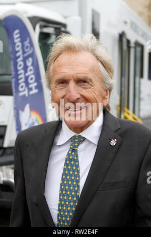 Derek Bell MBE, der äußerst erfolgreichen Rennfahrer, mit einem der Nächstenliebe Mobile Cancer Care Units, außerhalb der Kathedrale von Gloucester für die s geparkt Stockfoto