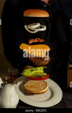 Sandwich mit fliegenden Zutaten auf weiße Platte angeboten Stockfoto