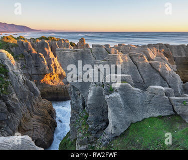 Beeindruckenden Sonnenuntergang über Felsformationen. Formen von geschichteten Fels Wissen als Pancake Rocks in Punakaiki, West Coast, Neuseeland. Stockfoto