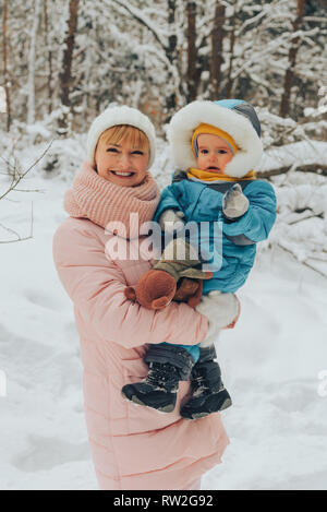 Mutter geht mit dem Kind im Winter in der Natur. Familie Spaziergänge in der Natur im Winter. Familie gehen. Winter Forest. Snow park. Stockfoto