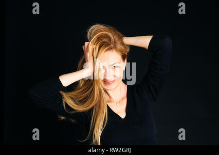 In der Nähe von Studio Portrait einer schönen Frau im schwarzen Kleid auf schwarzem Hintergrund Stockfoto