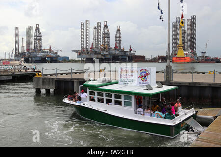 GALVESTON, Texas, USA - Juni 9, 2018: Touristen auf einem Baywatch Dolphin Tour Boot im Hafen von Galveston. Im Hintergrund Ölplattformen. Stockfoto