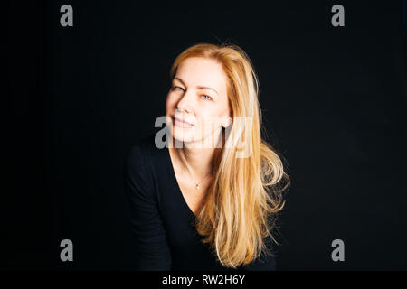 In der Nähe von Studio Portrait einer schönen Frau im schwarzen Kleid auf schwarzem Hintergrund Stockfoto