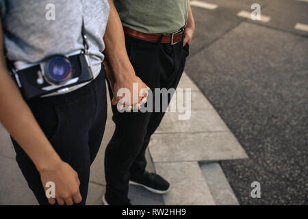 Junges Paar Hände halten beim Stehen auf einer Stadt Bürgersteig Stockfoto