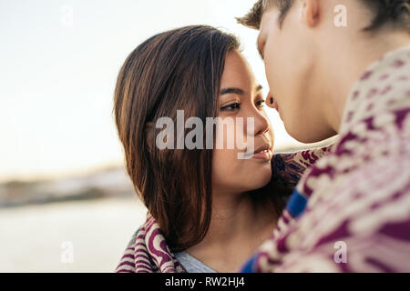 Junges Paar in eine Decke über Außen zu küssen gewickelt Stockfoto