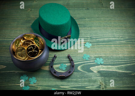 Happy St Patricks Day leprechaun hat mit Goldmünzen und Glücksbringer auf Vintage Style grün Holz Hintergrund. Ansicht von oben Stockfoto