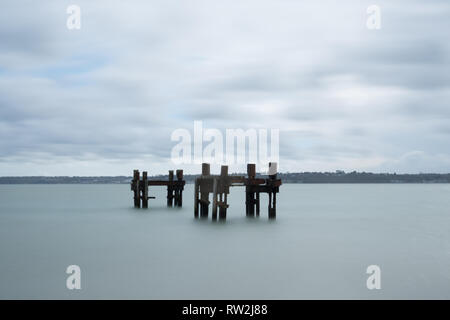 Die Reste von Strukturen aufgerufen, die Delphine im Meer weg von Lepe Strand, Teil der pierhead auf D-Tag im 2. Weltkrieg, Hampshire, Großbritannien Stockfoto