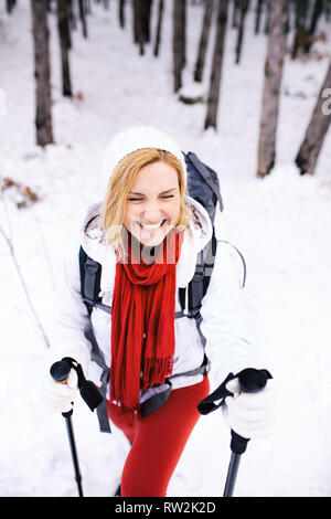 Mädchen in roten und weißen Outfit wandern in einem Wald mit Schnee an einem Wintertag Stockfoto