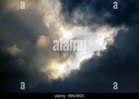Dunkle dramatische Himmel in einem stürmischen Abend mit einer Bohrung von Licht zwischen Clouds Stockfoto