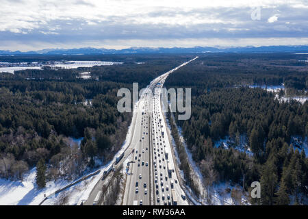 Luftaufnahme von Winter asphaltierte Landstraße oder Autobahn Straße in der Landschaft mit Autos und Cargo Logistik Lkw Zeit führenden zu bergen. Stockfoto