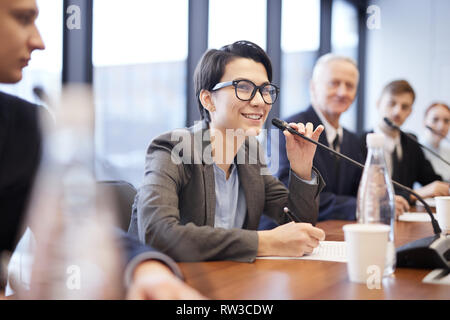 Portrait von lächelnden Geschäftsfrau zu sprechen Mikrofon während der Pressekonferenz oder Seminar, kopieren Raum Stockfoto