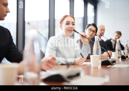 Portrait von lächelnden jungen Geschäftsfrau zu sprechen Mikrofon während der Pressekonferenz oder Seminar, kopieren Raum Stockfoto