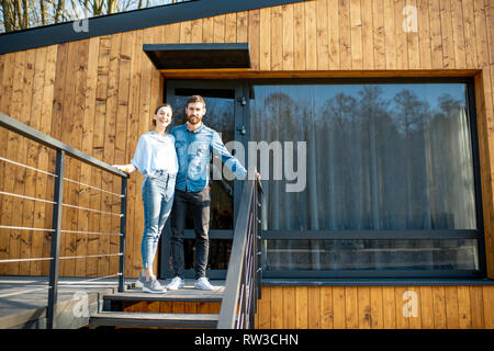 Portrait einer jungen und glückliches Paar stehen gemeinsam vor ihr modernes Haus im Freien Stockfoto