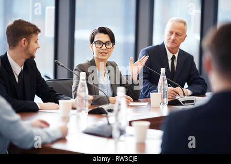 Porträt der jungen Geschäftsfrau zu sprechen Mikrofon während einer Diskussion im Konferenzraum, Raum kopieren Stockfoto