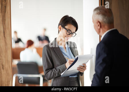 Taille bis Porträt der jungen Geschäftsfrau, die Zwischenablage im Gespräch mit Chef oder Business Coach, kopieren Raum Stockfoto