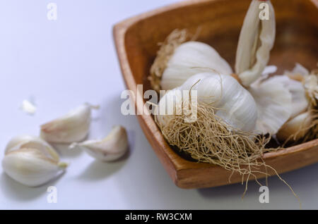 Knoblauch Zwiebeln in Houten auf weißem Hintergrund. Stapel von Knoblauch auf Tisch. Stockfoto