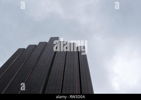 Ein anonymer, generischer, hoher, dunkler Hochhaus mit Glasfront und übergiebeltem grauem bewölktem Himmel in Sydney, Australien Stockfoto