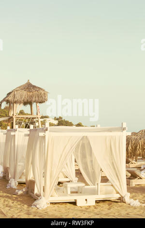 Den Strand mit dem weißen Betthimmeln Stockfoto