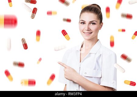 Junge Ärztin unter Pillen Regen über weißen Hintergrund. Stockfoto