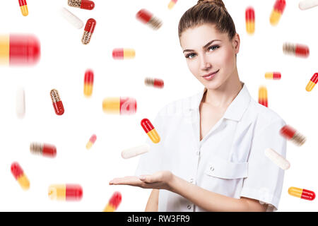 Junge Ärztin unter Pillen Regen über weißen Hintergrund. Stockfoto