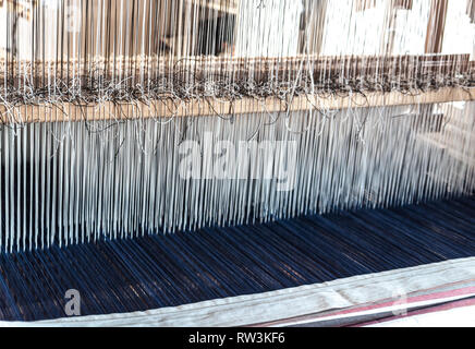 Detail einer alten traditionellen vintage Webstuhl mit vielen Baumwolle Zeichenfolgen in einem Holzrahmen als professioneller Handarbeit fertigungswerkzeug gebunden Stockfoto