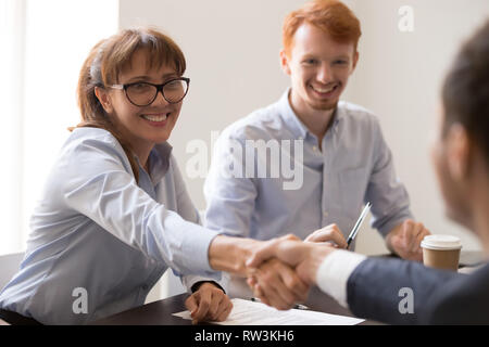 Lächelnde Frau mittleren Alters hr manager handshaking Einstellung männliche Antragsteller Stockfoto