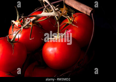 Große rote Tomaten auf schwarzem Hintergrund im Licht dunkel bereit zu kochen Stockfoto