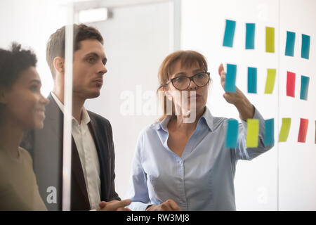 Im mittleren Alter Geschäftsfrau erklärt Projekt Strategie für Haftnotizen Stockfoto