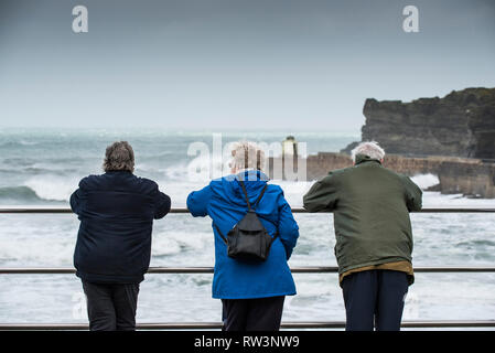 Leute, die sich der Ansatz der Sturm Freya wie starke Winde die Küste bei Portreath in Cornwall. Stockfoto