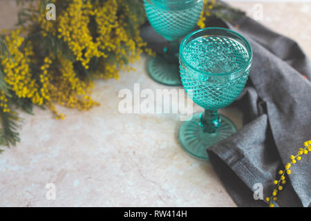 Blue Vintage Kelche und gelben Mimosen, Blumen. Weingläser auf whight Hintergrund. Stockfoto