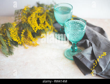 Blue Vintage Kelche und gelben Mimosen, Blumen. Weingläser auf whight Hintergrund. Stockfoto