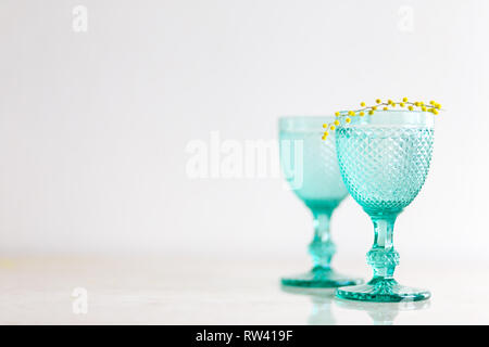 Blue Vintage Kelche und gelben Mimosen, Blumen. Weingläser auf whight Hintergrund. Stockfoto