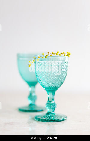 Blue Vintage Kelche und gelben Mimosen, Blumen. Weingläser auf whight Hintergrund. Stockfoto