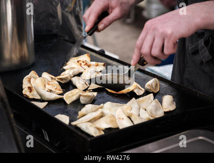 Frische gyozas, gebraten und mit Spachtel auf einer Heizplatte auf einem Straßenmarkt Garküche, Edinburgh, Schottland Stockfoto