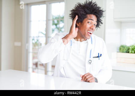 Afrikanische amerikanische Arzt Mann an der Klinik lächelnd mit der Hand über das Ohr zuhören eine Anhörung zu Gerücht oder Klatsch und Tratsch. Taubheit Konzept. Stockfoto