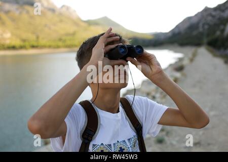 Junge mit dem Fernglas beobachten Wildtiere und Vögel auf einem schönen Fluss Stockfoto