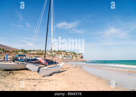 Katamaran auf Fuerteventura Strand mit einem schönen Resort im Hintergrund, Halbinsel Jandia, Spanien Stockfoto