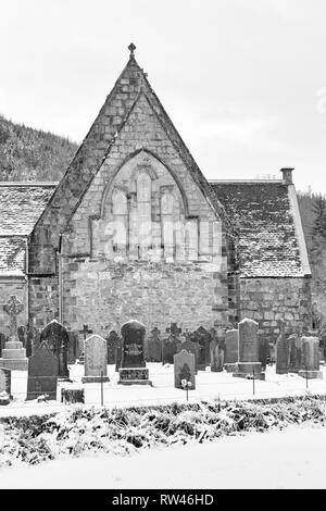ST John's Episcopal Church und Grabsteine im Schnee in Ballachulish, Highlands, Schottland, Großbritannien am Wintertag im Februar - Schwarzweiß monochrom Stockfoto
