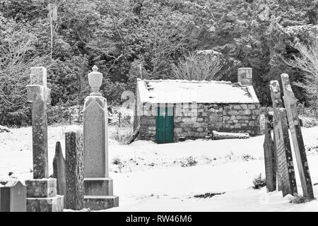 Kapelle auf dem Gelände der St John's Episcopal Church und Grabsteine im Schnee in Ballachulish, Highlands, Schottland, Großbritannien am Wintertag im Februar - B&W Stockfoto