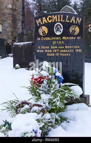 Grabstein im Schnee auf dem Kirchhof der St John's Episcopal Church, Ballachulish, Highlands, Schottland am Wintertag im Februar Stockfoto