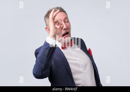 Älterer Mann im eleganten blauen Anzug mit OK. Er ist einverstanden mit Ihrer Wahl. Positiver menschlicher Emotionen. Stockfoto